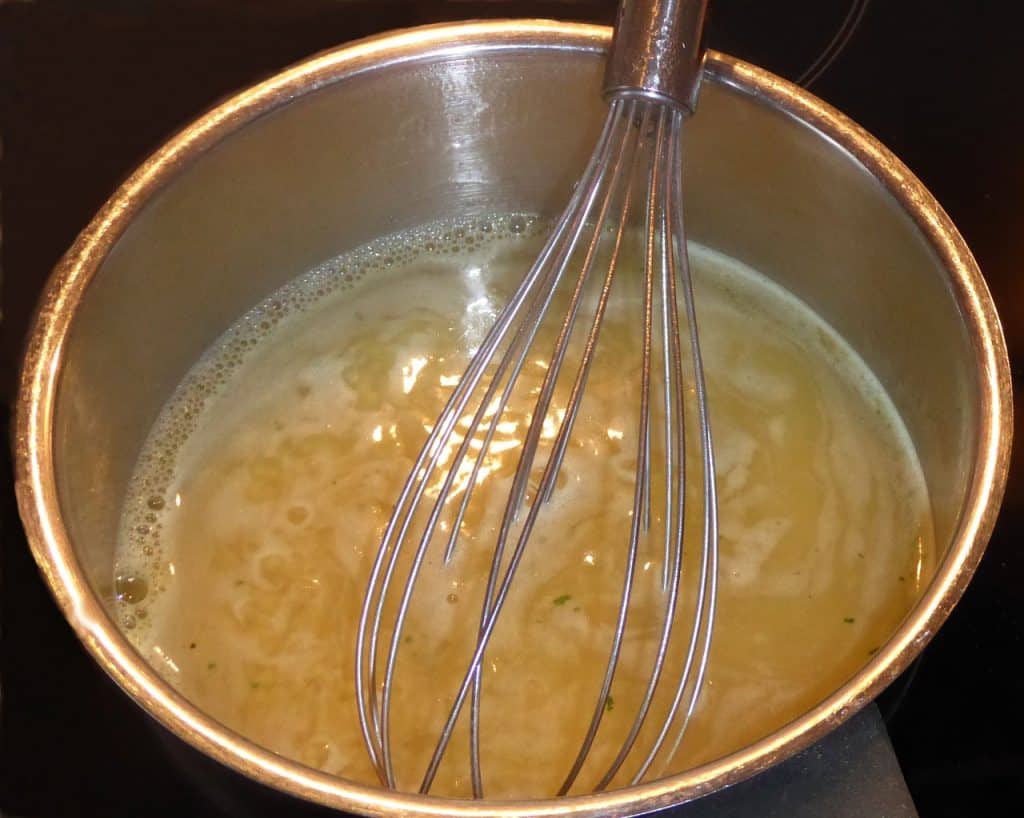 fresh homemade bone broth in a bowl with a whisk